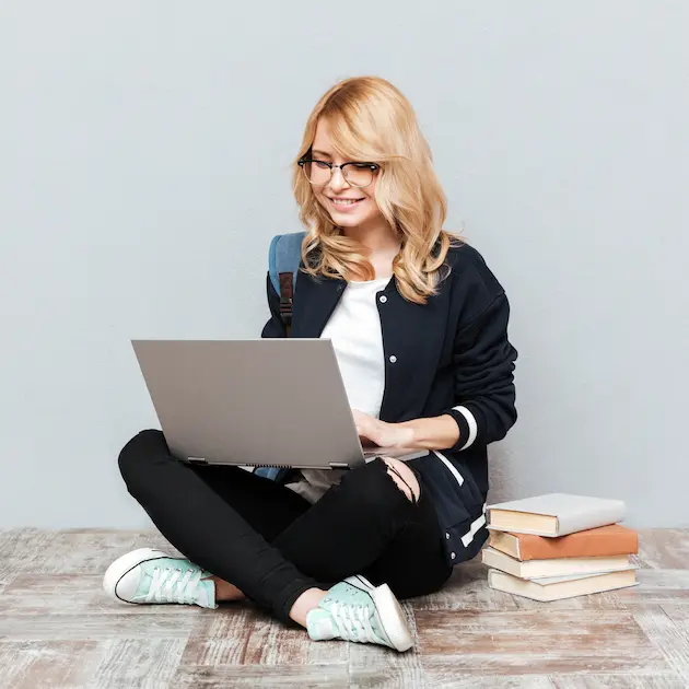 Uśmiechnięta kobieta z laptopem na kolanach